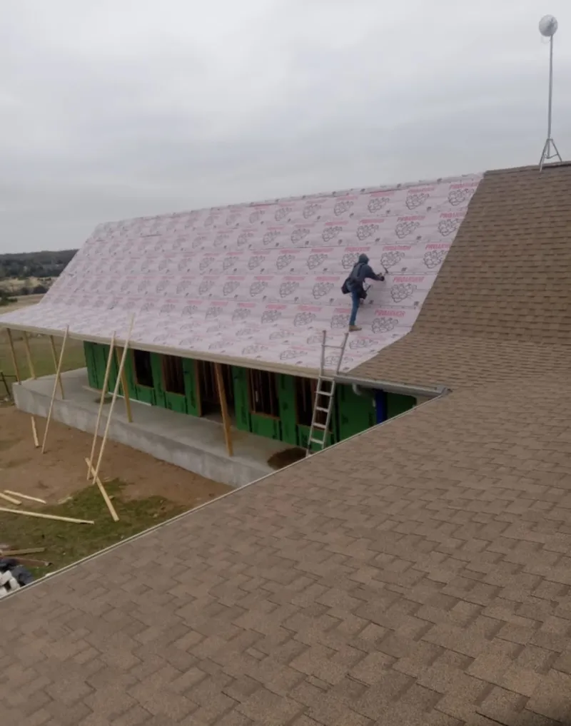 Worker preparing underlayment for a metal roof installation in West Richland